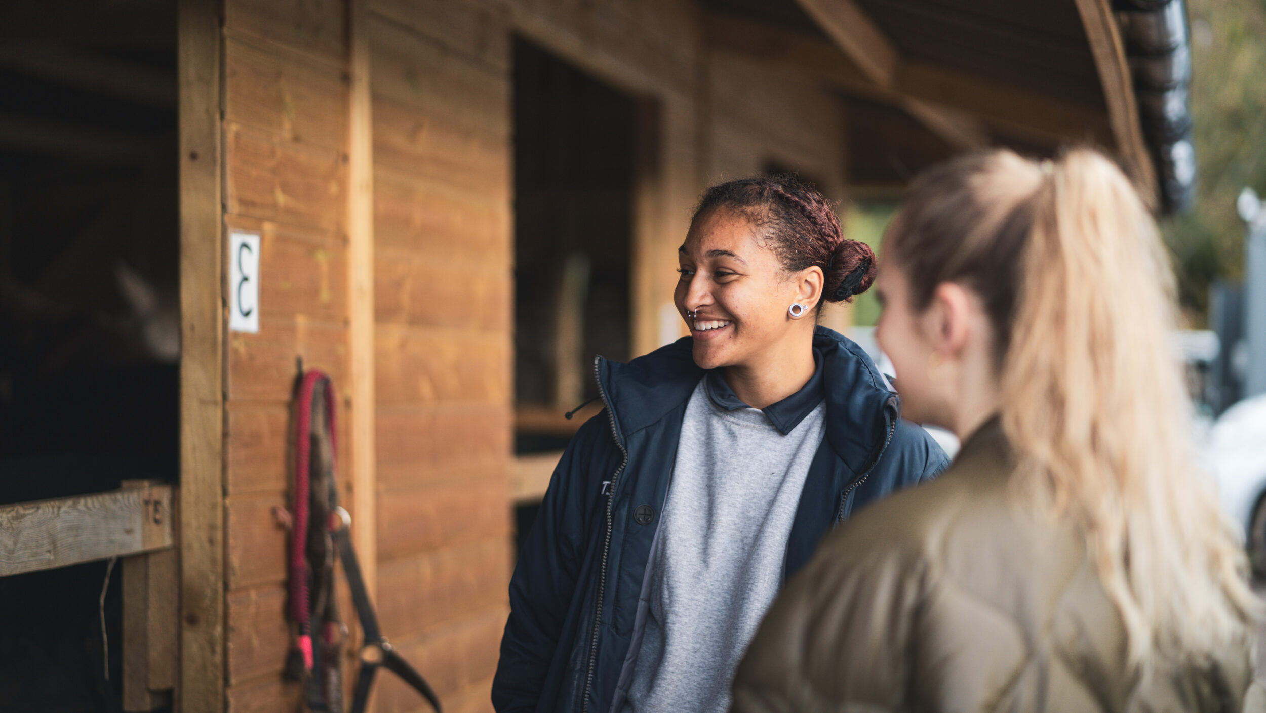 A support worker and a young person leading a horse across a paddock