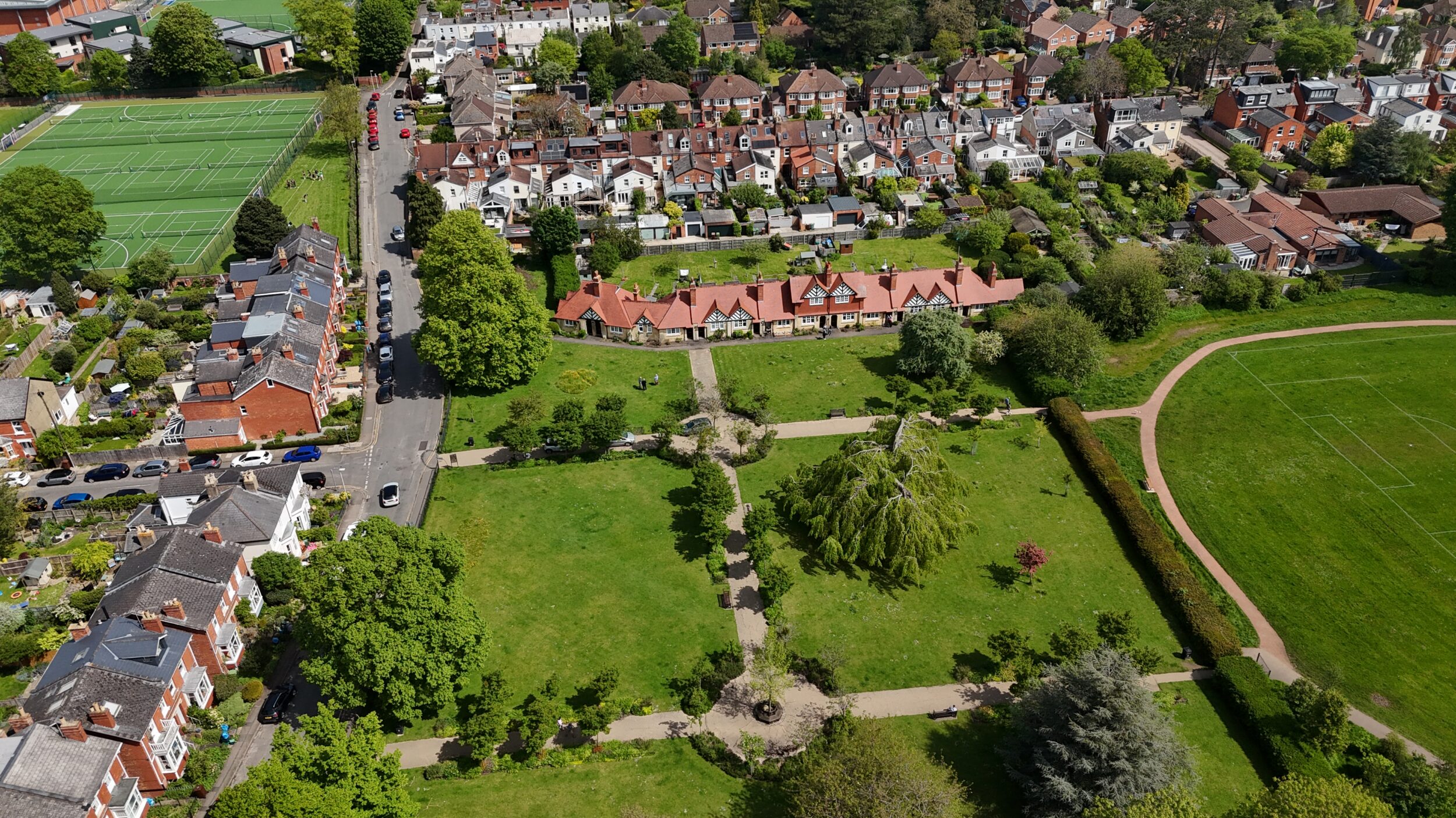 Wide drone shot of community cottages with surrounding houses and parkland