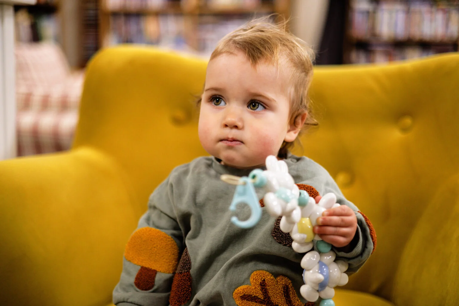 Baby sat on yellow chair with toy at a supported employment social enterprise
