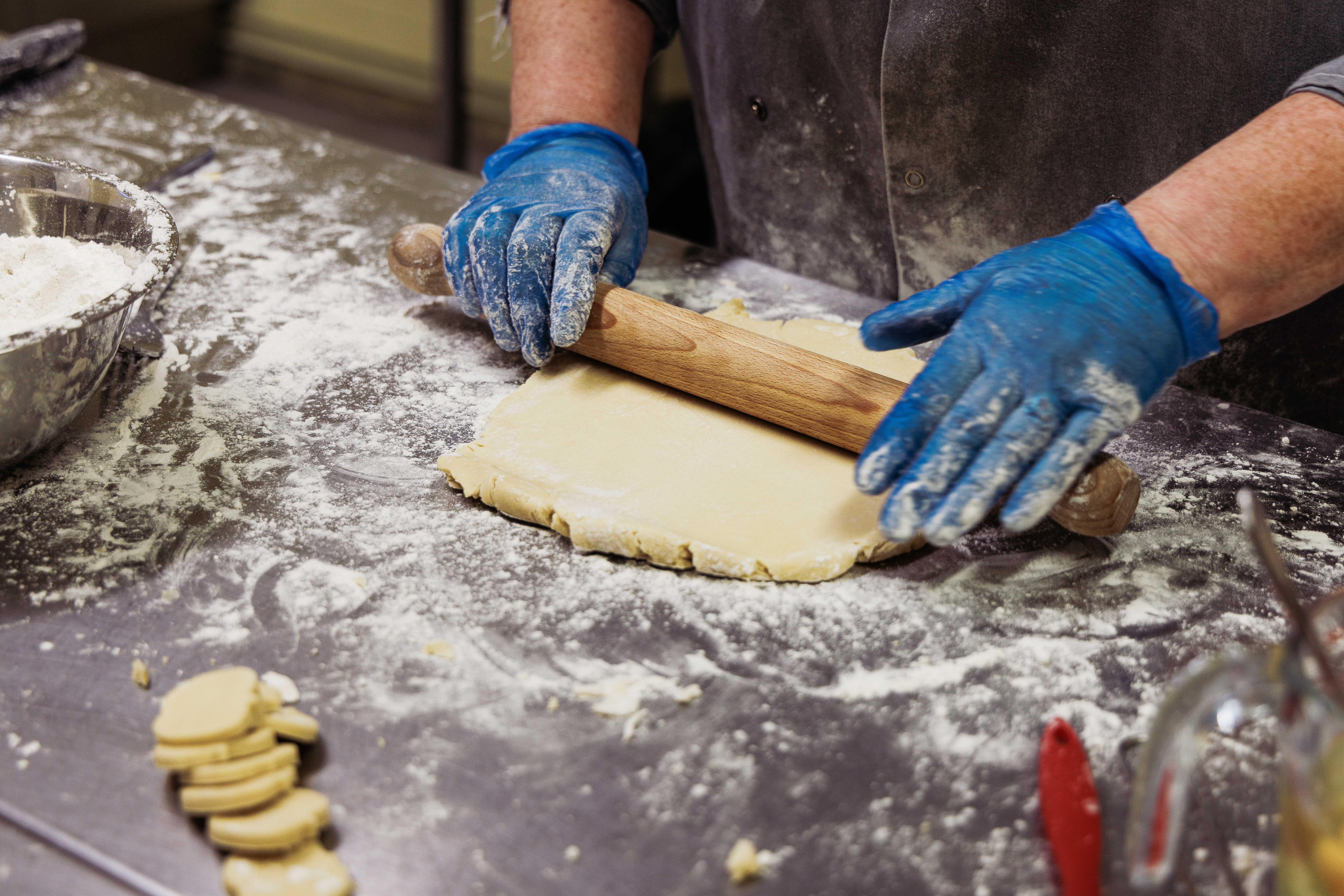Hands rolling out dough in the kitchen at a community bakery
